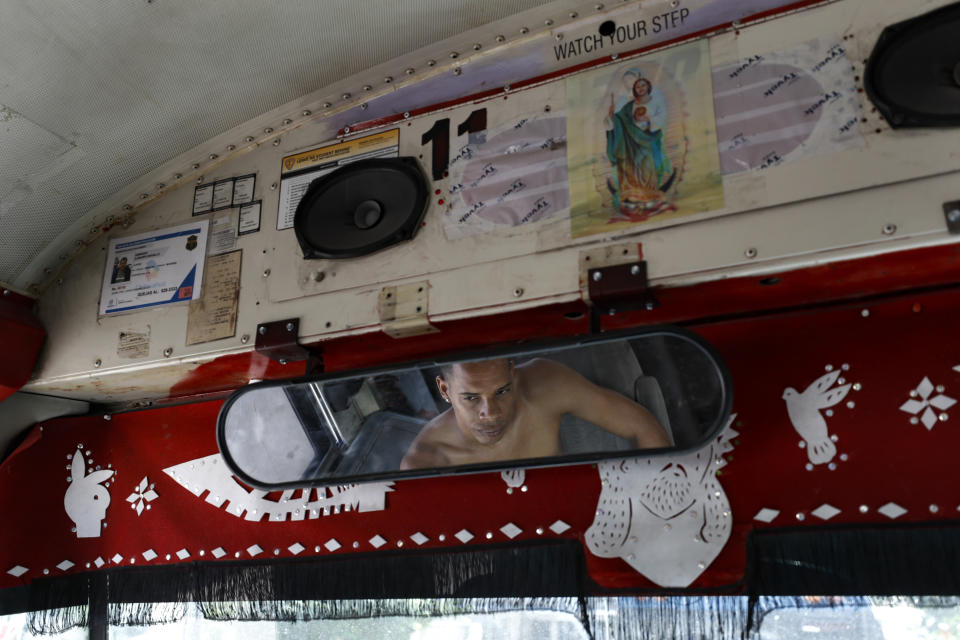 In this July 31, 2019, photo, a migrant from Cuba passes the day listening to music in a converted school bus parked near El Buen Pastor shelter for migrants in Cuidad Juarez, Mexico. (AP Photo/Gregory Bull)