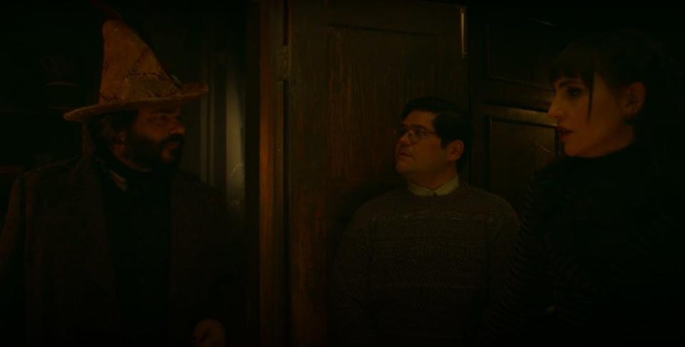 Laszlo, wearing his witch hat, talking to Nadja and Guillermo in "What We Do in the Shadows"