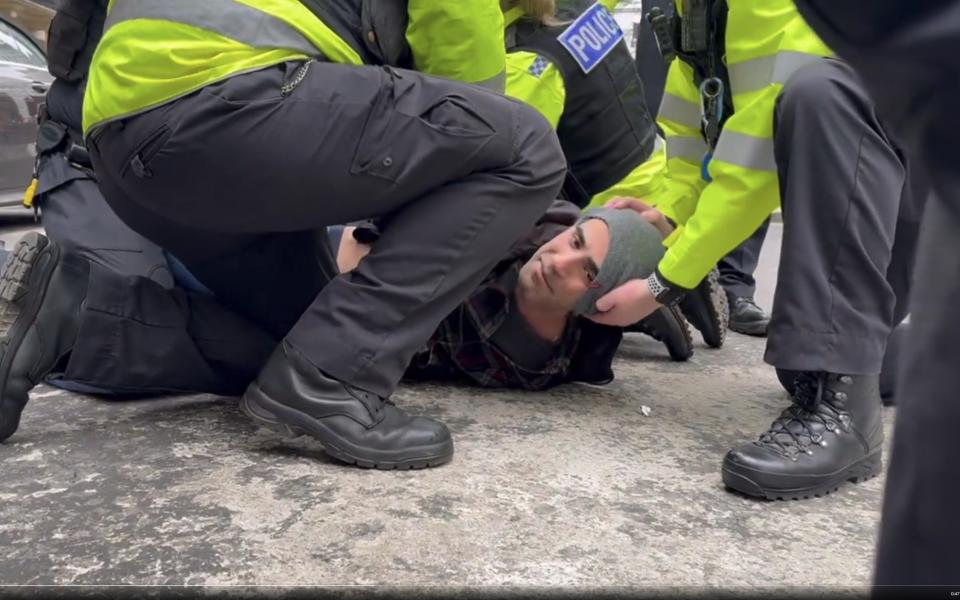 Niyak Ghorbani lies on the ground as he is handcuffed by police officers