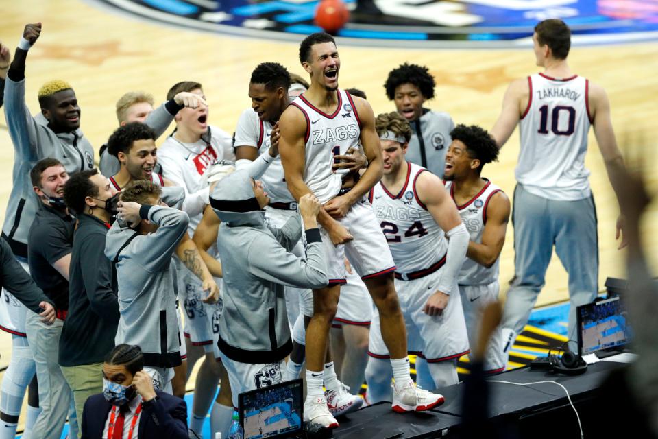 Gonzaga guard Jalen Suggs (1) leaps on a sideline table to celebrate after sinking a three-pointer at the buzzer to defeat UCLA in overtime during the 2021 men's NCAA Tournament national semifinals.