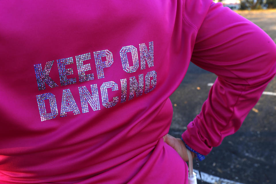 The words “Keep On Dancing” decorate on the back of Kathi Schmeling’s jacket as she marches at a practice of the Milwaukee Dancing Grannies on Wednesday, Nov. 2, 2022, in Milwaukee. Schmeling, 62, ran from the street to avoid injury when the driver of an SUV sped through the route of a Christmas parade last November in Waukesha, Wisconsin. The Grannies decided to regroup and dance again, partly to honor the three members of their group who were killed at the parade. One group member’s husband also was struck and killed. Said Schmeling, “None of us had to keep on dancing. We chose to do it because it's the joy it brings that trumps the sorrow.” (AP Photo/Martha Irvine)
