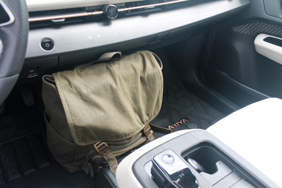 A backpack sits on the floor in between the front seats of the 2023 Nissan Ariya SUV.