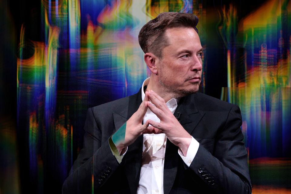 Elon Musk attends an event wearing a black jacket and white shirt. He tents his hands together and glances to the left. 