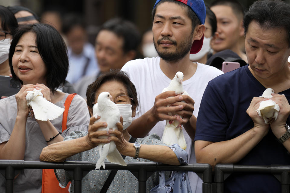 Visitors prepare to release doves in prayer of peace at the Yasukuni Shrine, which honors Japan's war dead, Tuesday, Aug. 15, 2023, in Tokyo. Japan holds annual memorial service for the war dead as the country marks the 78th anniversary of its defeat in the World War II. (AP Photo/Eugene Hoshiko)