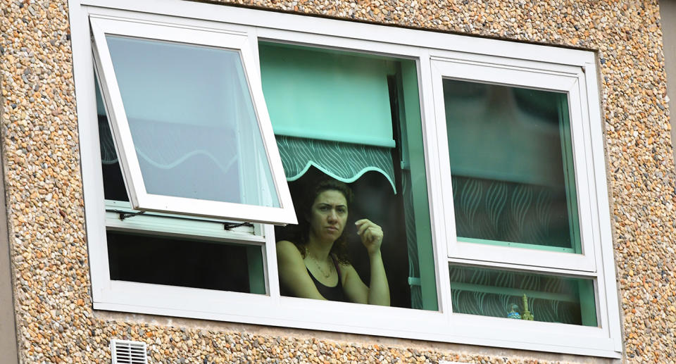 A woman looks out from a window inside a unit at the public housing tower along Racecourse Road in Melbourne. Source: AAP