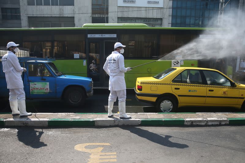 A member of the medical team wears protective face mask, following the coronavirus outbreak, as he sprays disinfectant liquid to sanitise a taxi car in Tehran