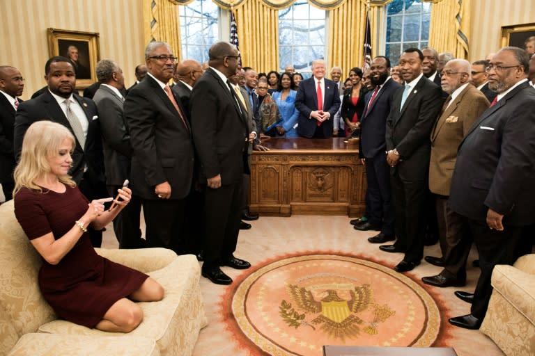 US President Donald Trump's senior advisor Kellyanne Conway (L) checks her phone after taking a photo as Donald Trump hosts leaders of historically black universities and colleges in the Oval Office on February 27, 2017