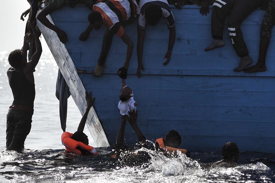 TOPSHOT - Migrants try to pull a child out of the water as they wait to be rescued by members of Proactiva Open Arms NGO in the Mediterranean sea, some 12 nautical miles north of Libya, on October 4, 2016. At least 1,800 migrants were rescued off the Libyan coast, the Italian coastguard announced, adding that similar operations were underway around 15 other overloaded vessels. / AFP / ARIS MESSINIS        (Photo credit should read ARIS MESSINIS/AFP/Getty Images)