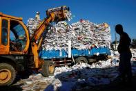 A worker watches an excavator load paper and cardboard onto a truck at a recycling yard at the edge of Beijing, China, August 19, 2016. REUTERS/Thomas Peter/Files