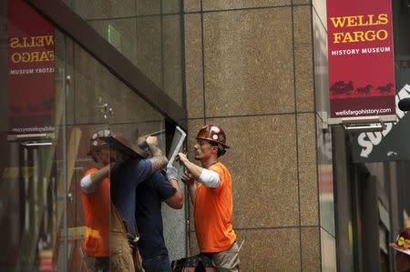 Workers remove shattered glass from the entrance to the Wells Fargo History Museum in San Francisco, California January 27, 2015. REUTERS/Robert Galbraith