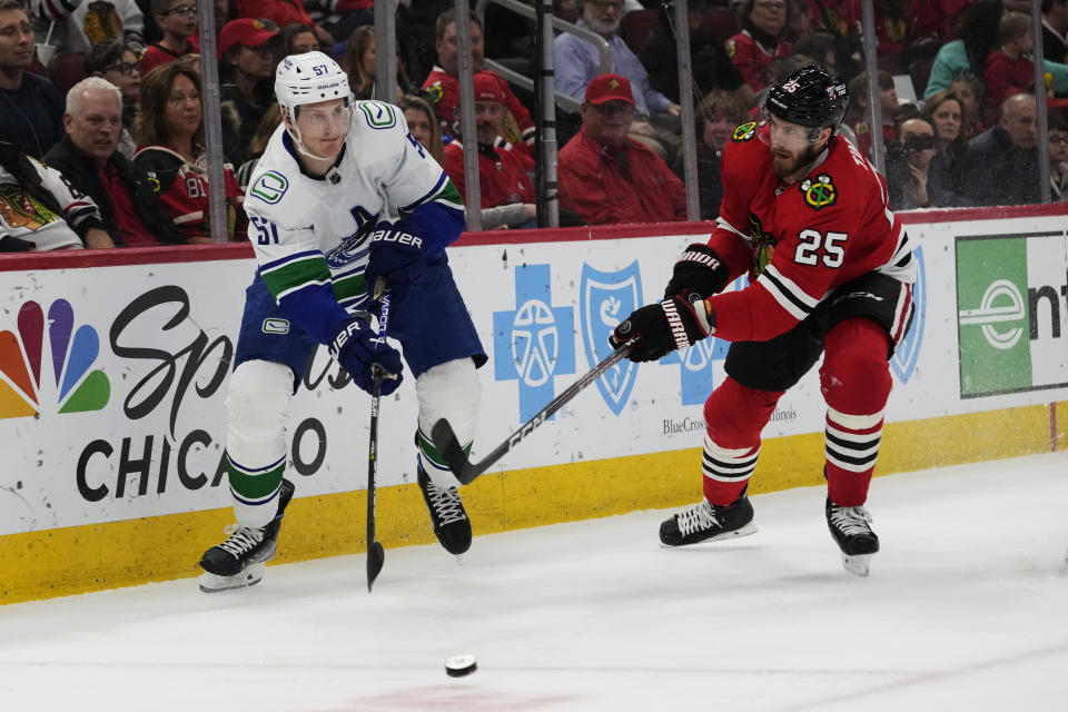 Vancouver Canucks defenseman Tyler Myers, left, passes the puck against Chicago Blackhawks defenseman Jarred Tinordi during the first period of an NHL hockey game in Chicago, Sunday, March 26, 2023. (AP Photo/Nam Y. Huh)