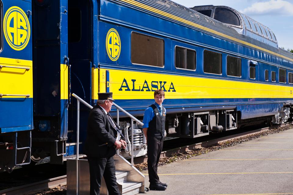 Conductor and clerk welcome passengers aboard an Alaska Railroad train.