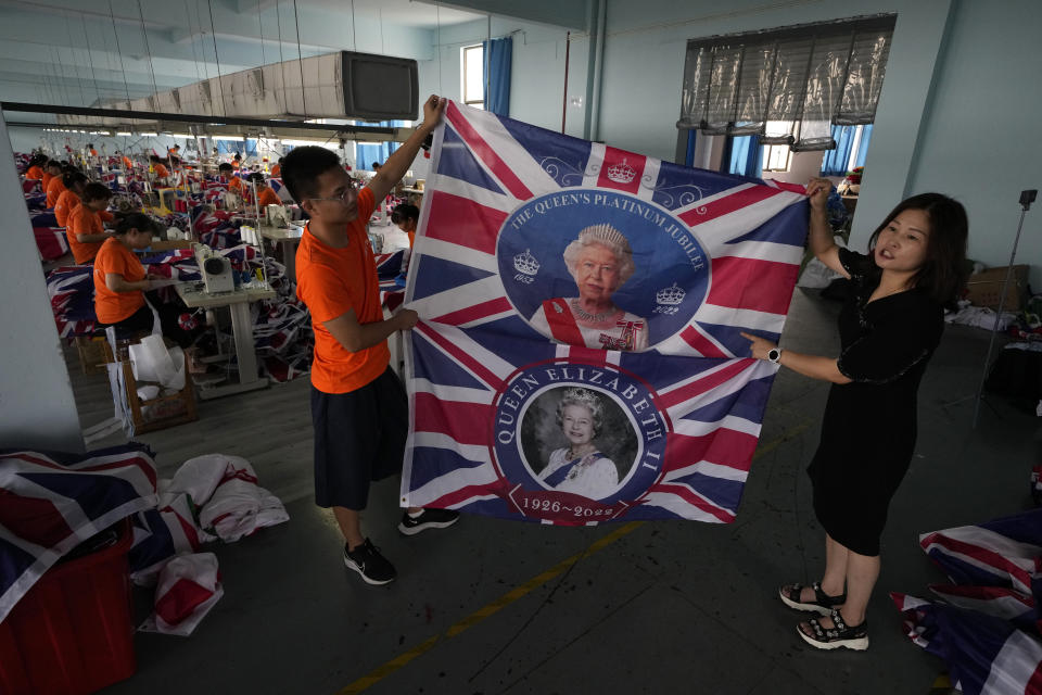 General manager Fan Aiping holds up flags with the Queen's image at the Shaoxing Chuangdong Tour Articles Co. factory in Shaoxing, in eastern China's Zhejiang province, Friday, Sept. 16, 2022. Ninety minutes after Queen Elizabeth II died, orders for thousands of British flags started to flood into the factory south of Shanghai. (AP Photo/Ng Han Guan)