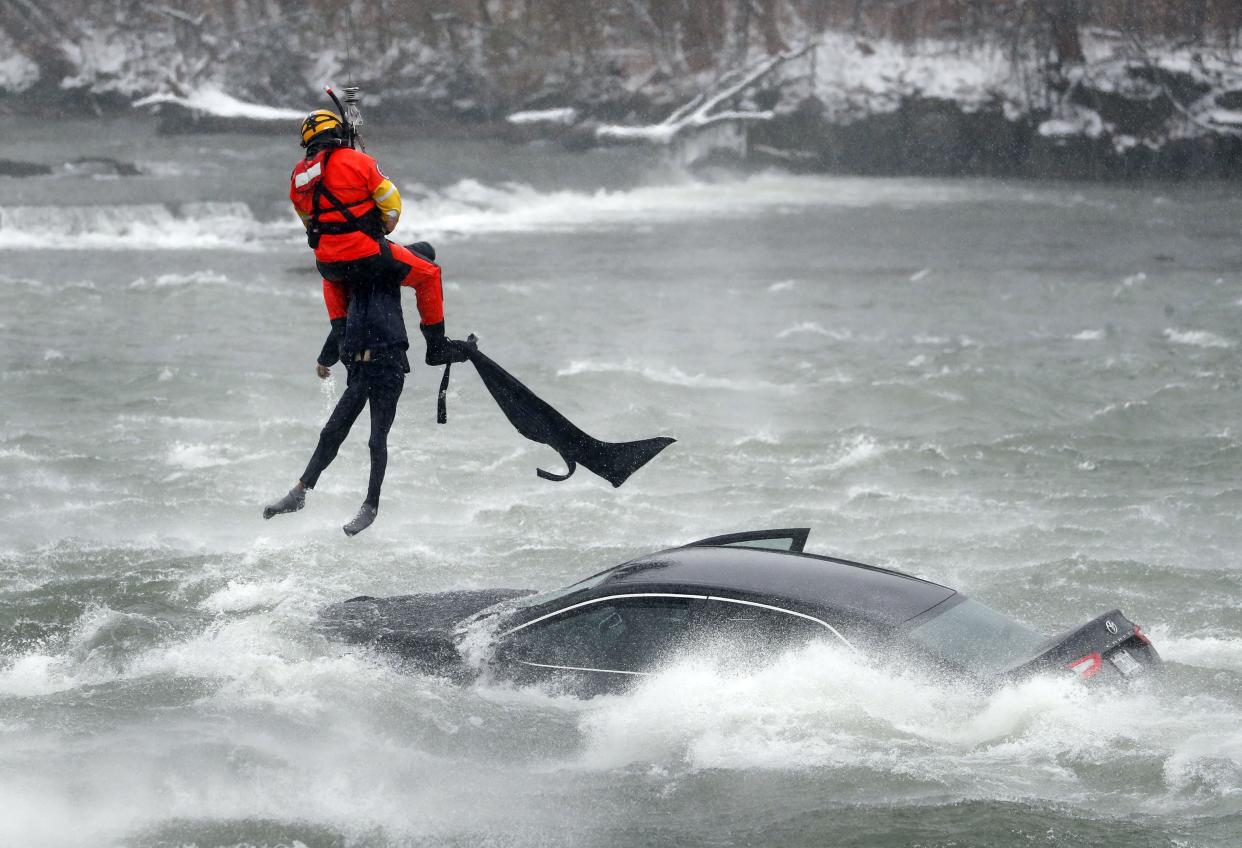 A U.S. Coast Guard diver, tethered to a hovering helicopter,  pulls a body from a submerged vehicle stuck in rushing rapids just yards from the brink of American Falls, one of three waterfalls that make up Niagara Falls, on Wednesday.