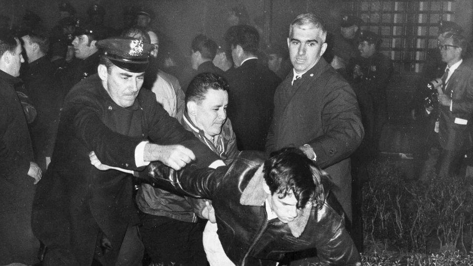 Police grab a youth as he tries to help a wounded man lying on the ground, after students holding a sit-in at Columbia University buildings were removed on April 30, 1968. - AP