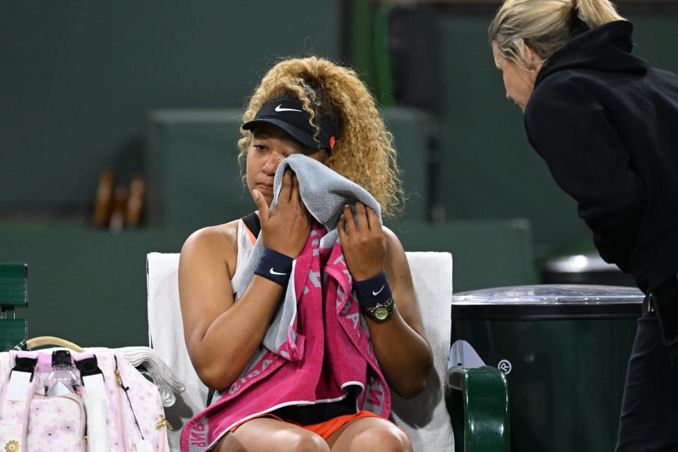 Naomi Osaka wipes her face as she talks to referee after a spectator disrupted play, yelling “Naomi you suck."