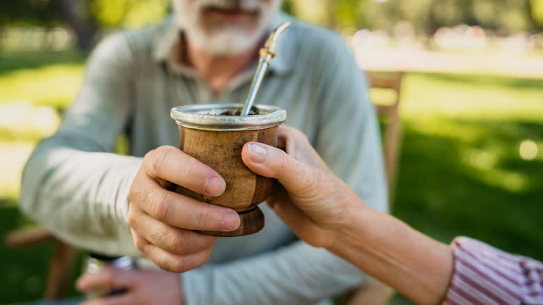 Man passing maté gourd to a woman