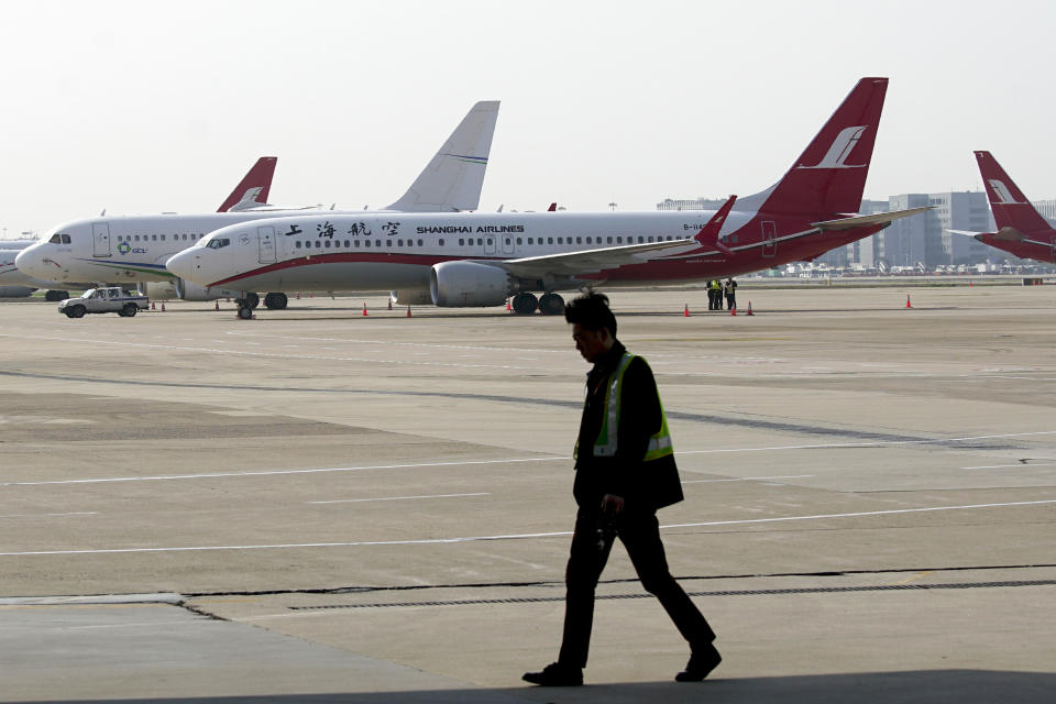 A ground crew walks near a Boeing 737 Max 8 plane operated by Shanghai Airlines parked on the tarmac at Hongqiao airport in Shanghai, China, Tuesday, March 12, 2019. U.S. aviation experts on Tuesday joined the investigation into the crash of an Ethiopian Airlines jetliner that killed 157 people, as a growing number of airlines grounded the new Boeing plane involved in the crash. (AP Photo)