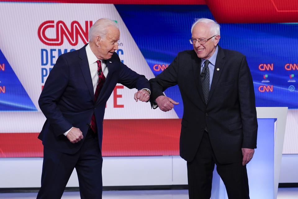 FILE - Former Vice President Joe Biden, left, and Sen. Bernie Sanders, I-Vt., right, greet one another before they participate in a Democratic presidential primary debate at CNN Studios in Washington, Sunday, March 15, 2020. (AP Photo/Evan Vucci, File)