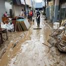 People clean a muddy street after heavy rains in Hitoyoshi