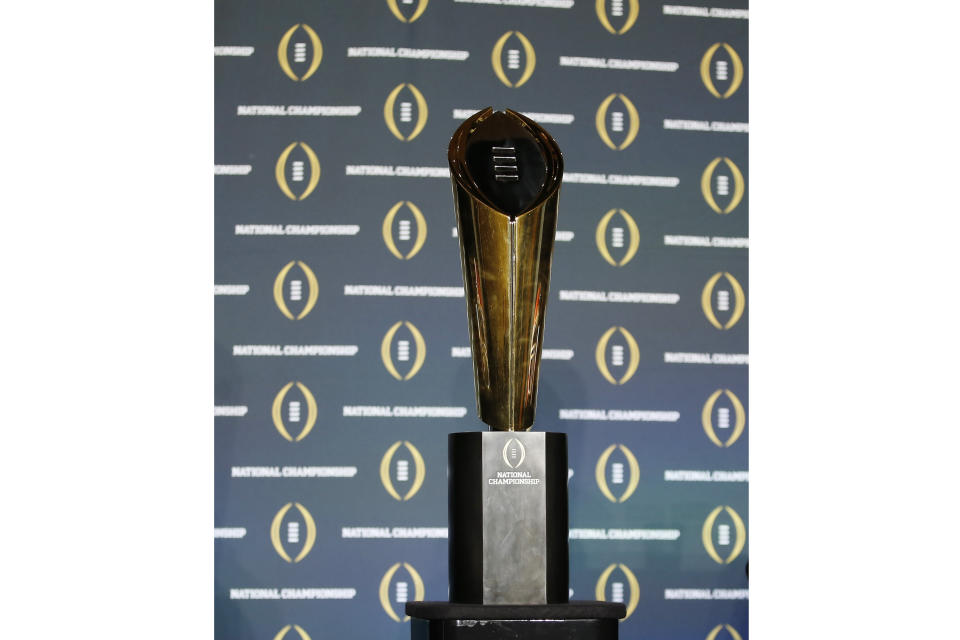 FILE - The national championship trophy is seen before a new conference for the NCAA college football playoff championship game between Clemson and Alabama, Sunday, Jan. 10, 2016, in Glendale, Ariz. The university presidents who oversee the College Football Playoff voted Friday, Sept. 2, 2022, to expand the postseason model for determining a national champion from four to 12 teams no later than the 2026 season.(AP Photo/David J. Phillip, File)