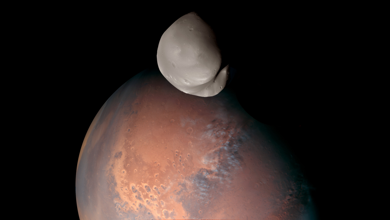  picture of mars with a potato-shaped moon in front of it 