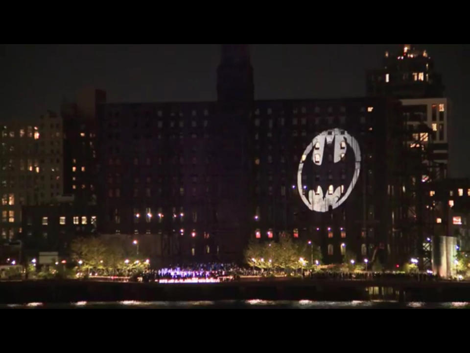 This image made from video provided by WPIX-TV shows the Batman signal projected on the Domino Sugar Refinery in honor of Batman Day in the Brooklyn borough of New York on Saturday, Sept. 21, 2019. The night sky all over the world is lighting up Saturday with an illumination of the famed bat insignia to mark a special anniversary for Batman. DC Comics is carrying off a celebration of Batman Day to mark the 80th anniversary of the appearance of crimefighter Bruce Wayne and his masked hidden identity. (WPIX-TV via AP)