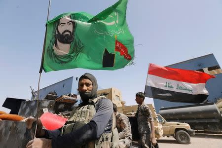 A Shi'ite fighter stands next to a religious flag near Falluja, Iraq, May 24, 2016. REUTERS/Thaier Al-Sudani