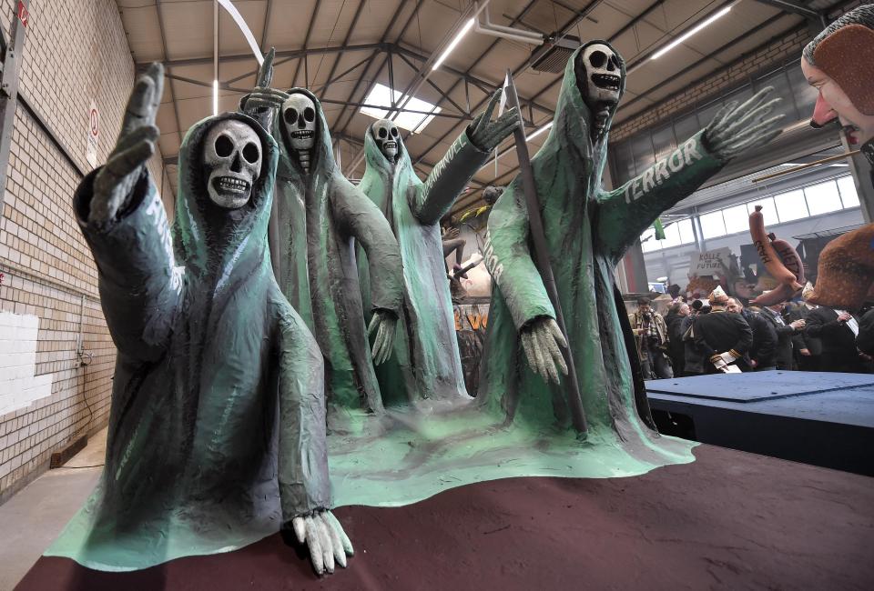 A satiric carnival float depicting terror, hunger and climate change, is shown during a preview in a hall in Cologne, Germany, Tuesday, Feb. 18, 2020. The traditional carnival parades on Rosemonday make fun of politics and are watched by hundreds of thousands in the streets of Cologne, Duesseldorf and Mainz. (AP Photo/Martin Meissner)