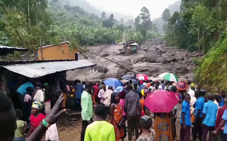 In this image made from video, residents look at a river filled with mud in Bududa District, Uganda, Friday, Oct. 12, 2018. At least 30 people died in mudslides triggered by torrential rains in a mountainous area of eastern Uganda that is prone to such disasters, a Red Cross official said Friday. More victims were likely to be discovered when rescue reams access all the affected areas in the foothills of Mount Elgon, said Red Cross spokeswoman Irene Nakasiita. (AP Photo)