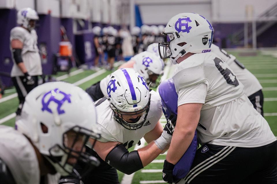 Holy Cross' Christo Kelly, left, works with Sean Woods during football spring practice last week.