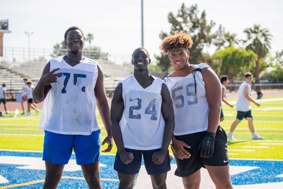 Matthew Lado (left), Adam Mohammed and Michael Watkins pose for a photo during football practice at the Apollo High School football field in Glendale on Thursday, April 27, 2023.