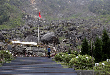 A visitor stands in front of the site of Beichuan Middle School which was buried by boulders in the 2008 Sichuan earthquake, in the city of Beichuan, Sichuan province, China, April 6, 2018. REUTERS/Jason Lee