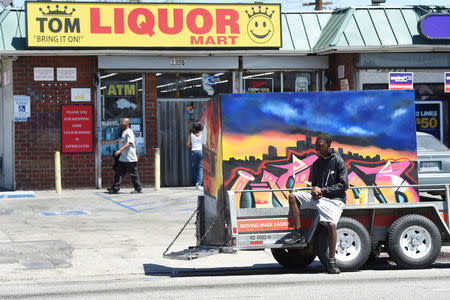 A marcher sits next to a painting depicting Los Angeles Riots waiting for the start of a march from the intersection of Florence and Normandie Avenue, the flashpoint where the riots started 25 years ago, to remember and honor the victims of the 1992 Los Angeles riots in Los Angeles, California, U.S., April 29, 2017. REUTERS/Kevork Djansezian