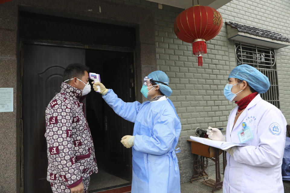 FILE - In this Jan. 27, 2020 photo, community health workers check the temperature of a person who recently returned from Hubei Province, center of a virus outbreak, in Hangzhou in eastern China's Zhejiang Province. As China institutes the largest quarantine in human history, locking down more than 50 million people in the center of the country, those who have recently been to Wuhan are being tracked, monitored, turned away from hotels and shoved into isolation at their homes and in makeshift quarantine facilities. (Chinatopix via AP)