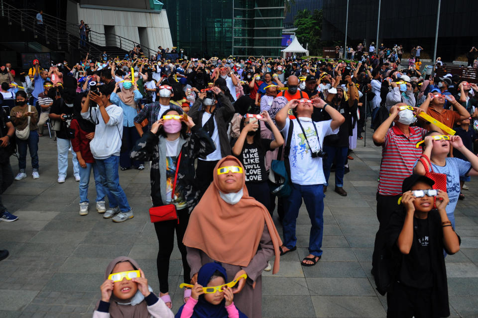 People wear protective glasses to watch a partial hybrid solar eclipse at Ismail Marzuki Park in Jakarta, Indonesia on April 20, 2023.