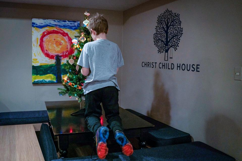 A 9-year-old boy, whose identity is kept anonymous for safety reasons, decorates a Christmas tree at Christ Child House in Detroit on Monday, Dec. 12, 2022.