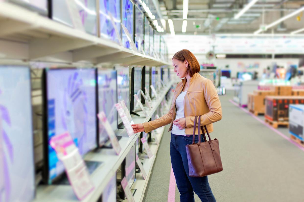 Woman shopping in an electronics store and looking at tvs