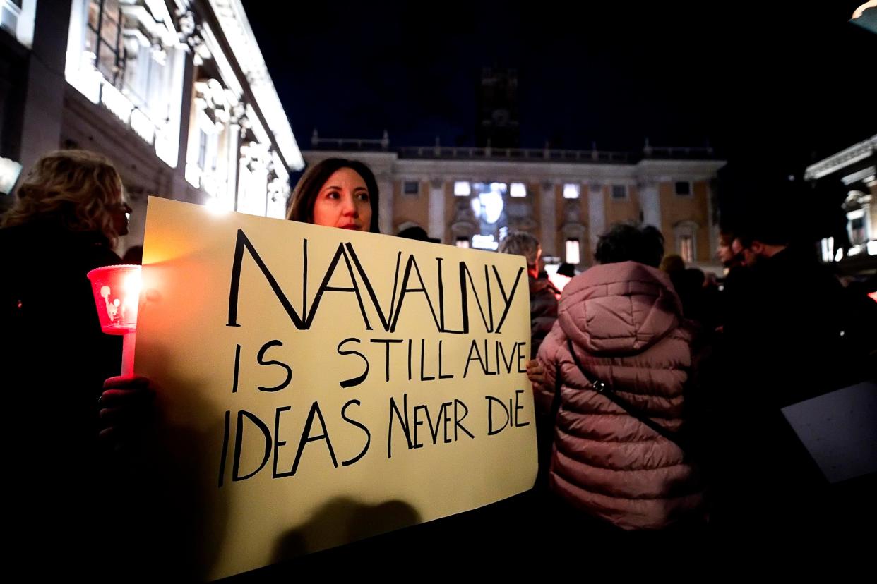 A person holds a sign as they attend a torchlight procession in memory of Russian opposition leader Alexei Navalny (EPA)