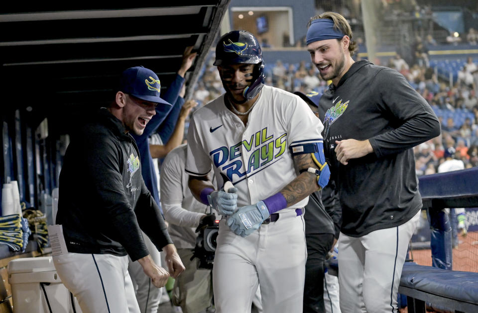 Tampa Bay Rays' Ben Rortvedt, left, and Josh Lowe, right, congratulate Jose Siri, center, in the dugout after his solo home run off Washington Nationals starter Mitchell Parker during the second inning of a baseball game Friday, June 28, 2024, in St. Petersburg, Fla. (AP Photo/Steve Nesius)