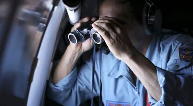 Vietnamese Air Force Col. Pham Minh Tuan uses binoculars on board a flying aircraft during a mission to search for the missing Malaysia Airlines flight MH370 in the Gulf of Thailand. Photo: AP.