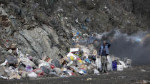 A trash collector stands at the burning landfill near Priboj, in southwest Serbia, Friday, Jan. 22, 2021. Serbia and other Balkan nations are virtually drowning in communal waste after decades of neglect and lack of efficient waste-management policies in the countries aspiring to join the European Union. (AP Photo/Darko Vojinovic)