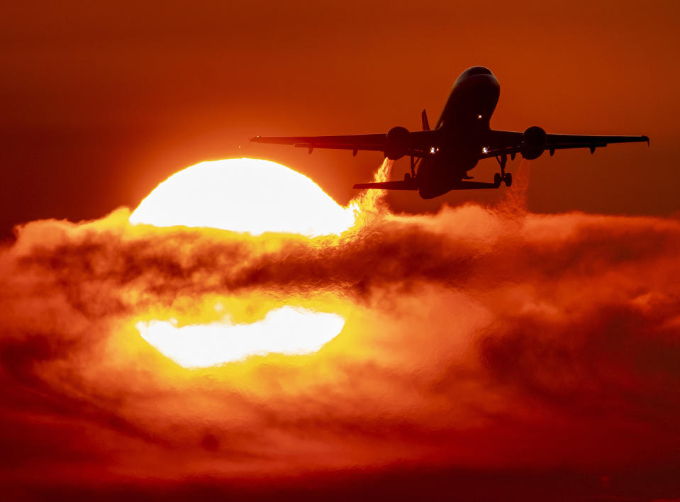 FILE - In this Sept. 19, 2019 file photo, an aircraft passes the rising sun during take off at the international airport in Frankfurt, Germany. Germany’s top court has ruled that the government has to set clear goals for reducing greenhouse gas emissions after 2030, arguing that current legislation doesn’t go far enough in curbing climate change. (AP Photo/Michael Probst, File)