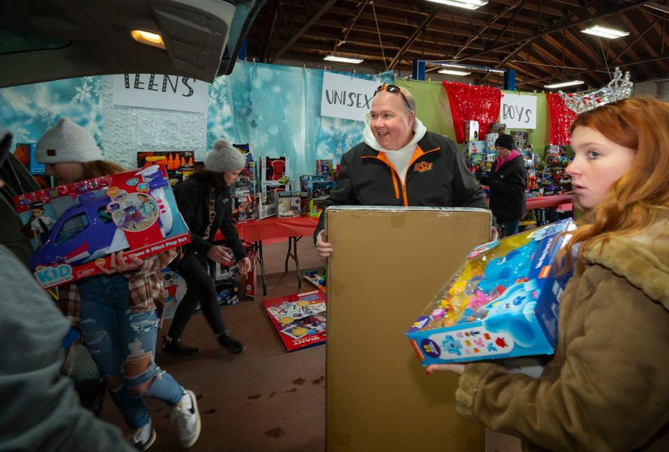 Pittsburg County 4-H leader Greg Owen, center, and Hensley Kidd, Miss Teen McAlester, load toys into cars at the 2021 4-H toy giveaway.