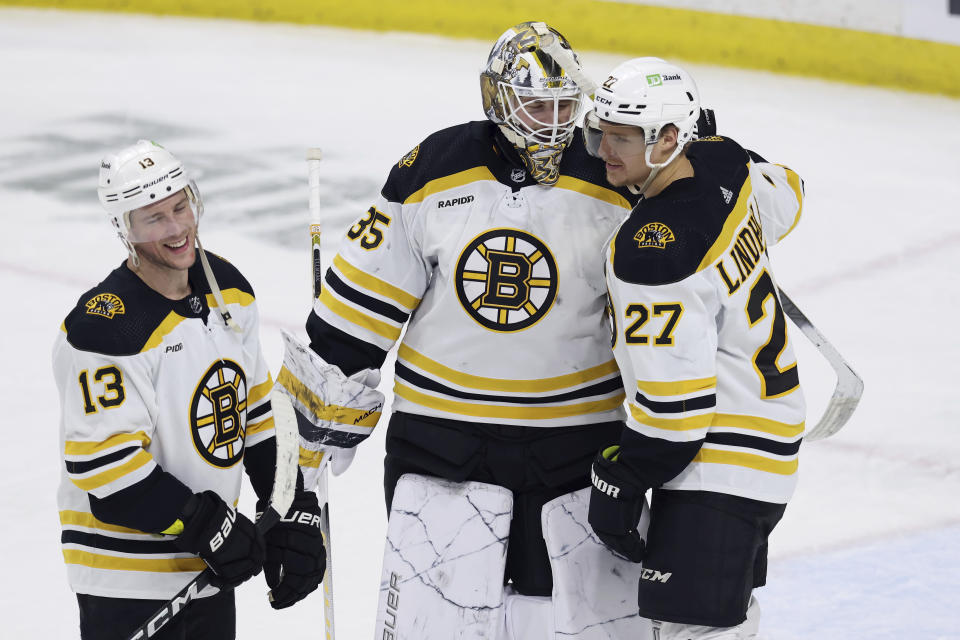 Boston Bruins goaltender Linus Ullmark (35) celebrates with teammates center Charlie Coyle (13) and defenseman Hampus Lindholm (27) after winning 5-2 over the Minnesota Wild in an NHL hockey game Sunday, March 18, 2023, in St. Paul, Minn. (AP Photo/Stacy Bengs)
