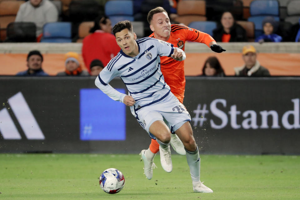 Sporting Kansas City forward Daniel Salloi, left, advances the ball in front of Houston Dynamo forward Corey Baird, right, during the first half of an MLS playoff soccer match Sunday, Nov. 26, 2023, in Houston. (AP Photo/Michael Wyke)