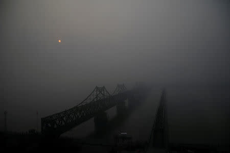 FILE PHOTO: The sun rises through fog over the Friendship and the Broken bridges over the Yalu River connecting the North Korean town of Sinuiju and Dandong in China's Liaoning province, March 30, 2017. REUTERS/Damir Sagolj/File Photo