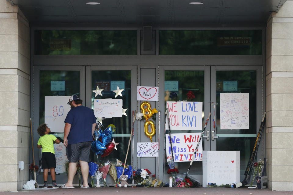 Zachary Hunter and his son Samuel visit a makeshift memorial in front of Nationwide Arena Monday, July 5, 2021, in Columbus, Ohio, to remember Columbus Blue Jackets goaltender Matiss Kivlenieks who died of chest trauma from an errant fireworks mortar blast in what authorities described Monday as a tragic accident on the Fourth of July. (AP Photo/Jay LaPrete)