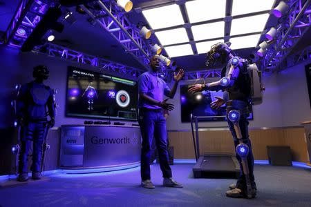 George Twopointoh (C), brand ambassador for Genworth, guides Ugo Dumont, a volunteer for the Genworth R70i Aging Experience, during a demonstration at the Liberty Science Center in Jersey City, New Jersey April 5, 2016. REUTERS/Shannon Stapleton