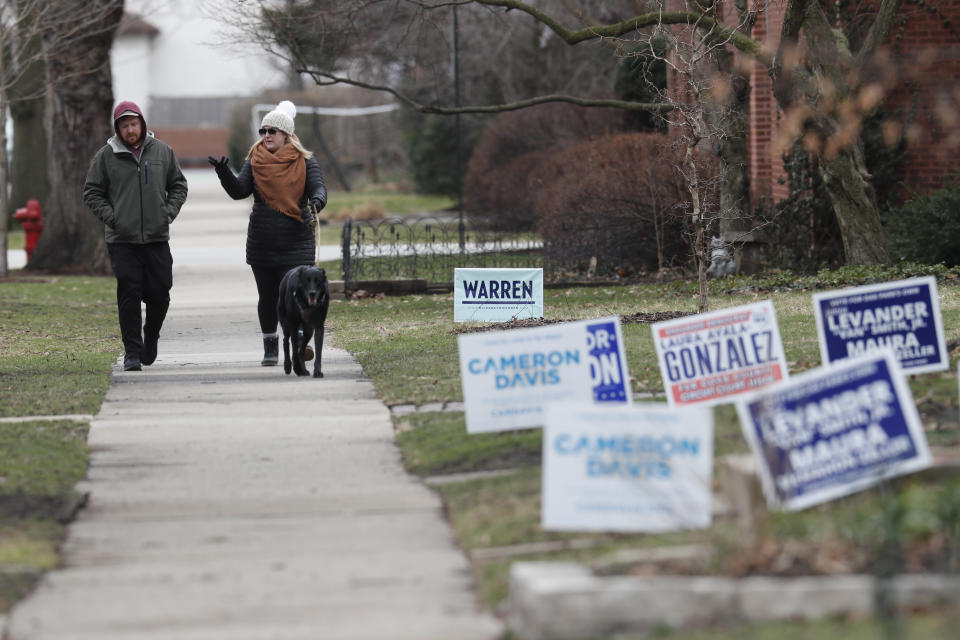 Village of Oak Park, Ill., residents Adam and Nicole Colleran walk their dog Brew Friday, March 20, 2020. There are at least three confirmed cases of COVID-19 in Oak Park, just nine miles from downtown Chicago, where the mayor has ordered residents to shelter in place. With so few tests available, surely there are others, says Tom Powers, spokesman for the village of about 52,000 in a metropolitan area with millions. (AP Photo/Charles Rex Arbogast)